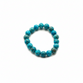 A beaded stretch bracelet made of round turquoise-blue stone beads with dark matrix, photographed on a plain white background.